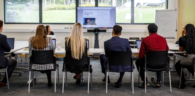 people in a room listening to a tutor on a course