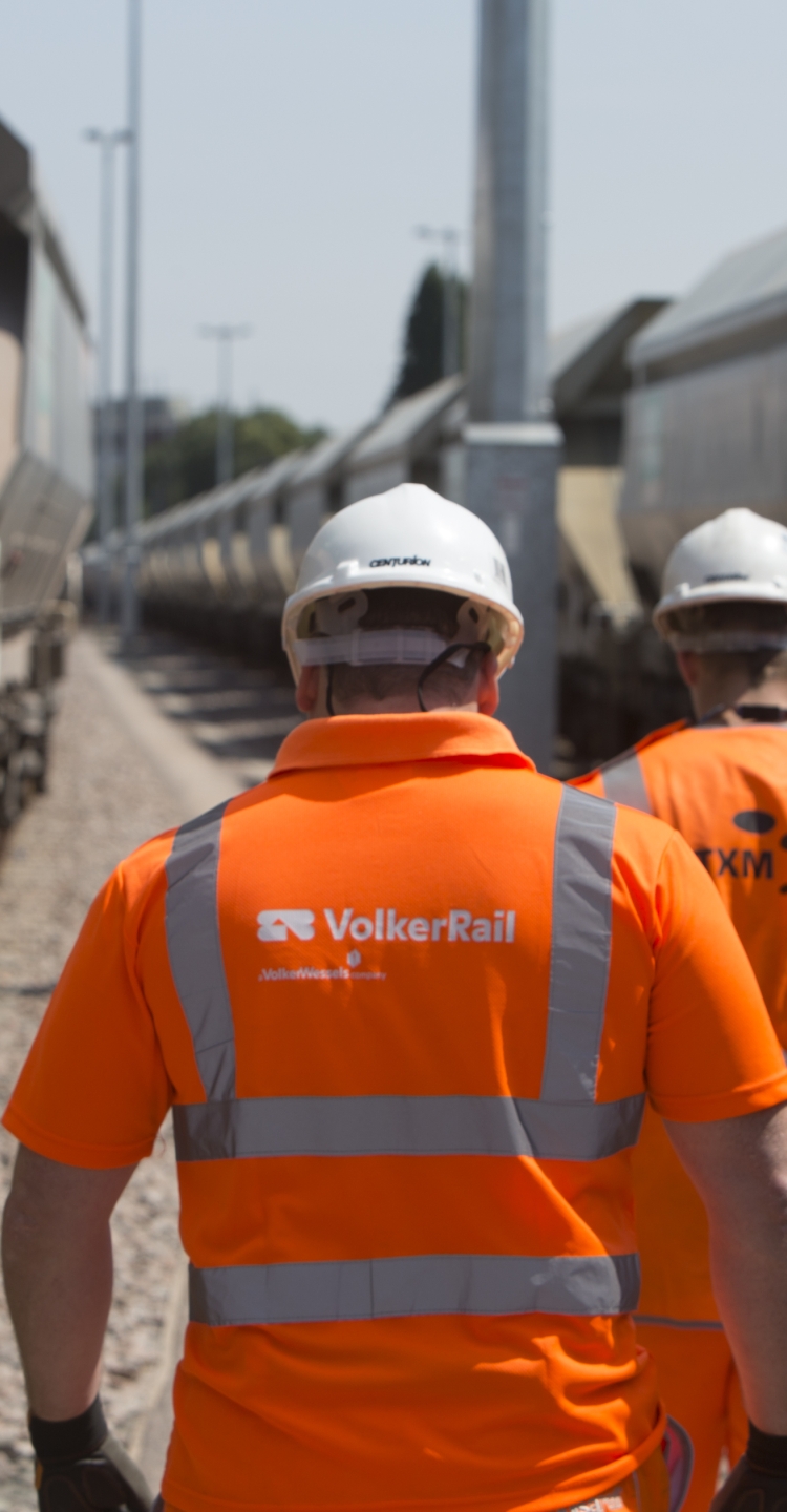 VolkerRail employee walking down site with his back to camera