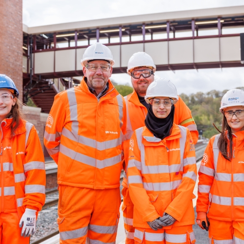 a group of smiling employees in PPE on a platform