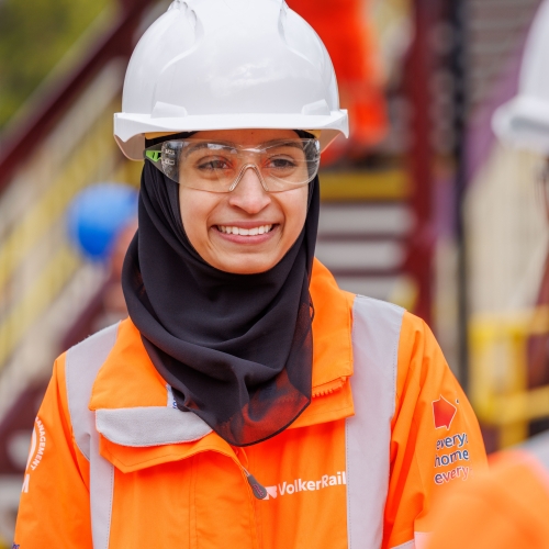 Two women in orange PPE talking on site