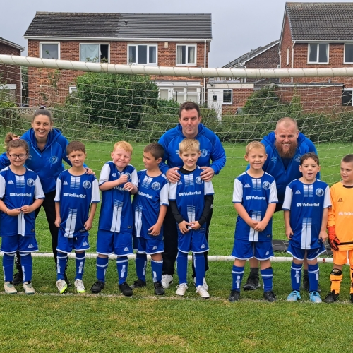 group of children in their new blue football kits in a goal