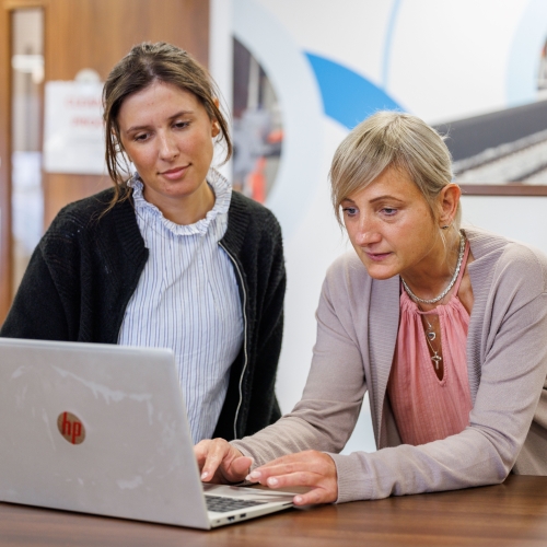 Two women looking at a laptop laughing