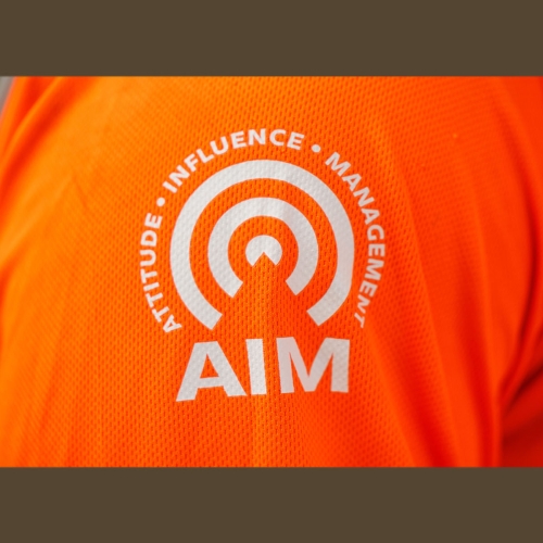 AIM logo on an orange PPE top