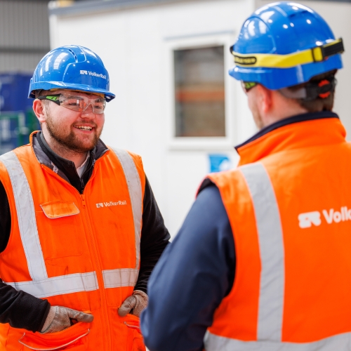 Two apprentices in orange PPE in a training facility