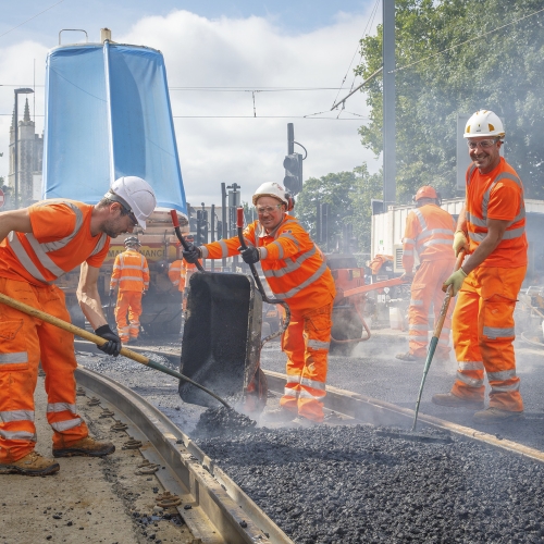 Men building a new track track in orange PPE and smiling
