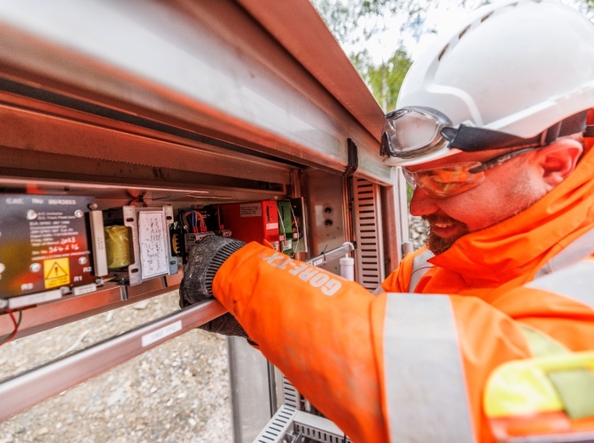A man working on a signalling REB unit smiling