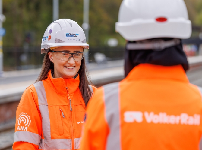 young women smiling to camera in orange PPE and blurred VolkerRail logo