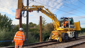 road rail vehicle with a piling hammer and a man in PPE watching