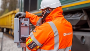 man in orange PPE testing telecoms equipment on track