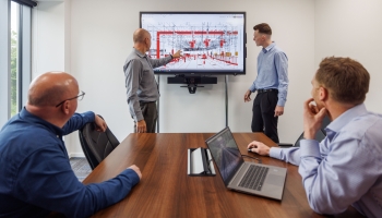 four men working on a rail track design on the computer