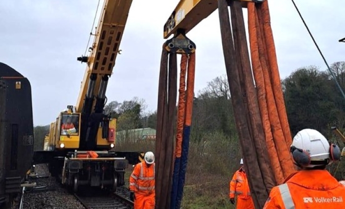 A passenger train being rerailed using a Kirow crane