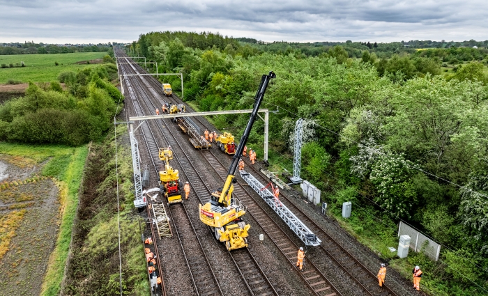 VolkerRail installing a gantry over track on a sunny day surrounded by trees