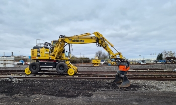 A Komatsu digging up the ground next to a railway