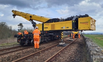 A passenger train being rerailed using a Kirow crane