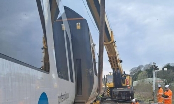 A passenger train being rerailed using a Kirow crane