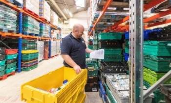 man working in a food back with a yellow box that he is filling