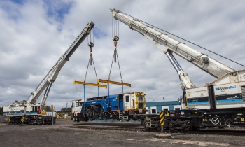 A beaver tamper being lifted onto track by two Kirow cranes working in tandem