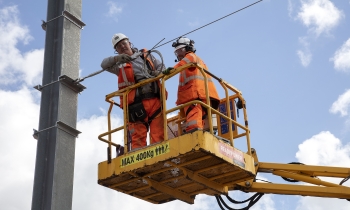 Two operatives in orange PPE working on an overhead line