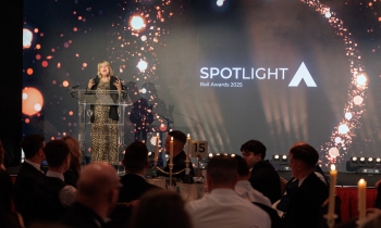 female presenter on stage with award logo behind her on a screen