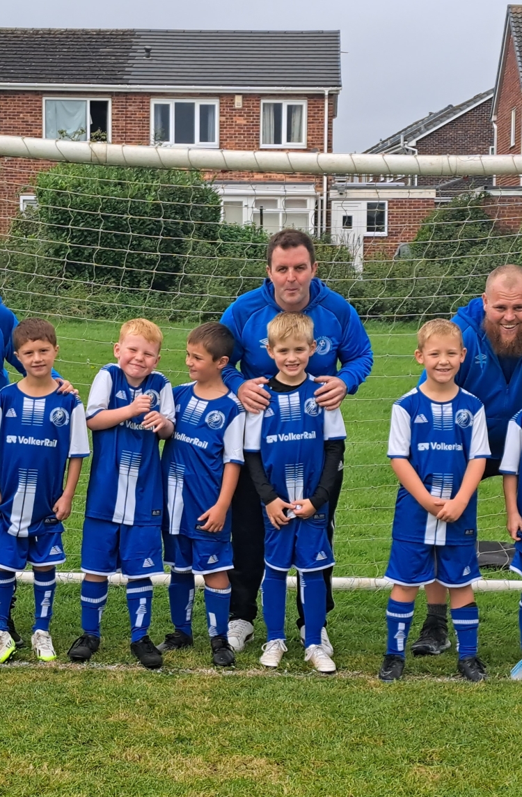 group of children in their new blue football kits in a goal