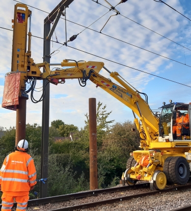 road rail vehicle with a piling hammer and a man in PPE watching