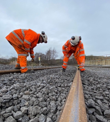 Two men in orange high vis checking the track