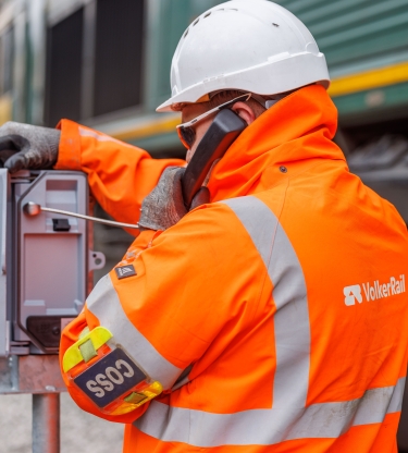 man in orange PPE testing telecoms equipment on track