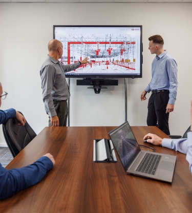 four men working on a rail track design on the computer