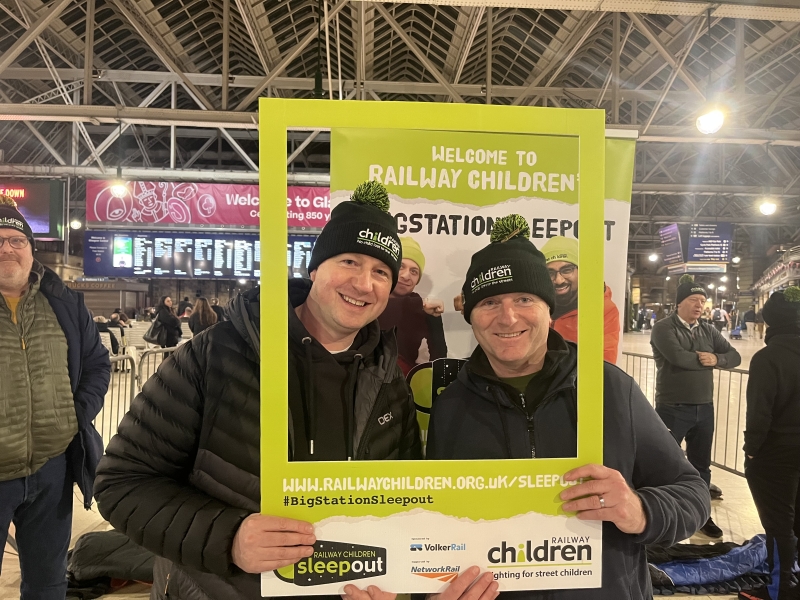 two employees posting for a picture in a sign