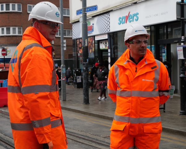 Two men in orange PPE on a tram site