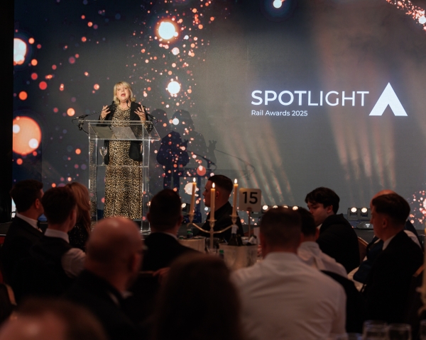 female presenter on stage with award logo behind her on a screen