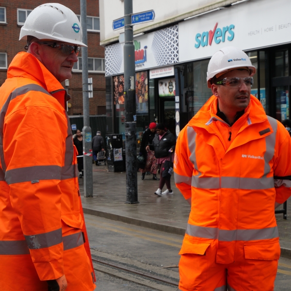 Two men in orange PPE on a tram site