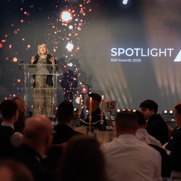 female presenter on stage with award logo behind her on a screen
