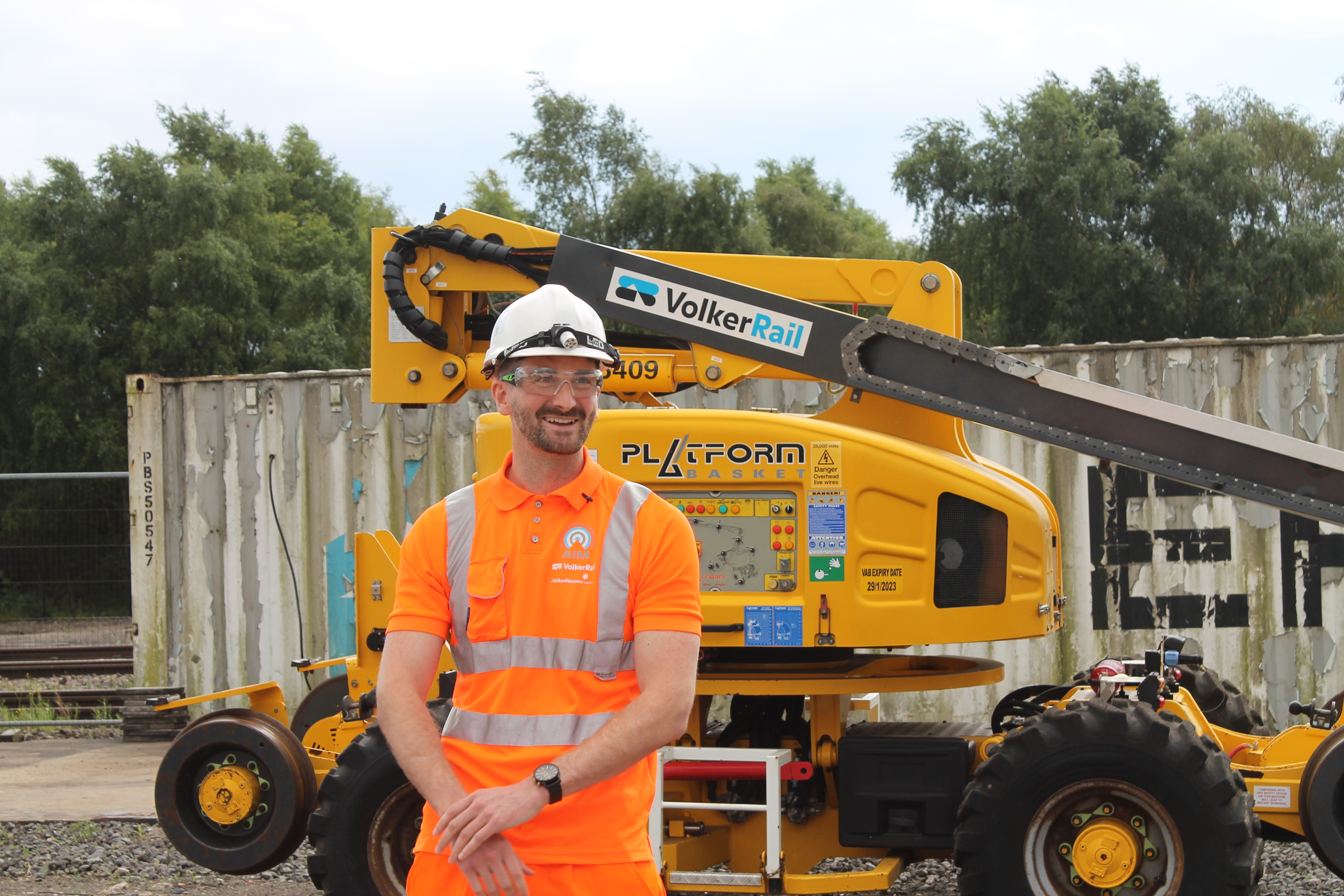 a man in PPE smiling in front of a yellow RRV
