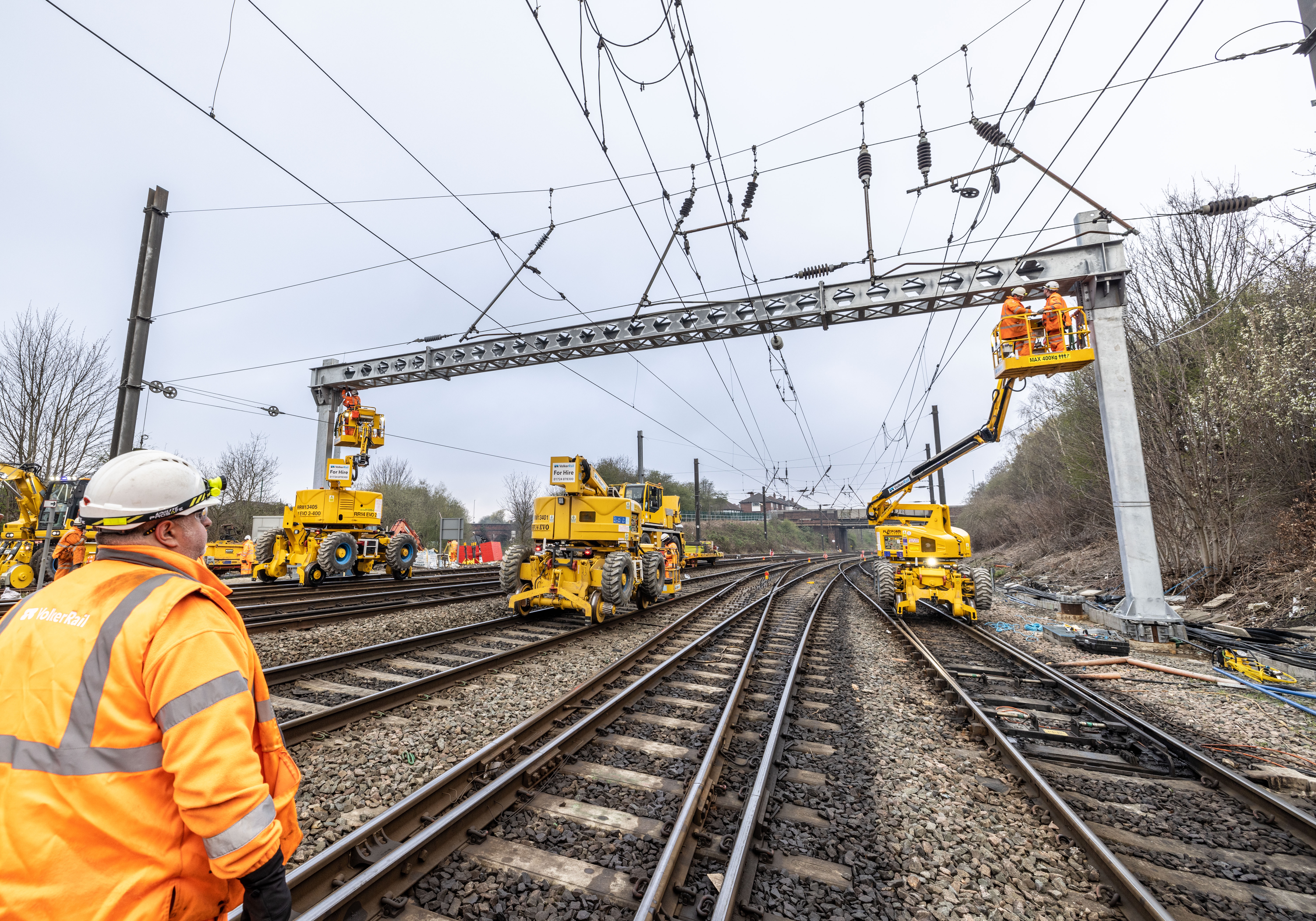 Rail operative looking up at an overhead line gantry being installed by VolkerRail using MEWPS and road rail vehicles on the Transpennine route upgrade project 