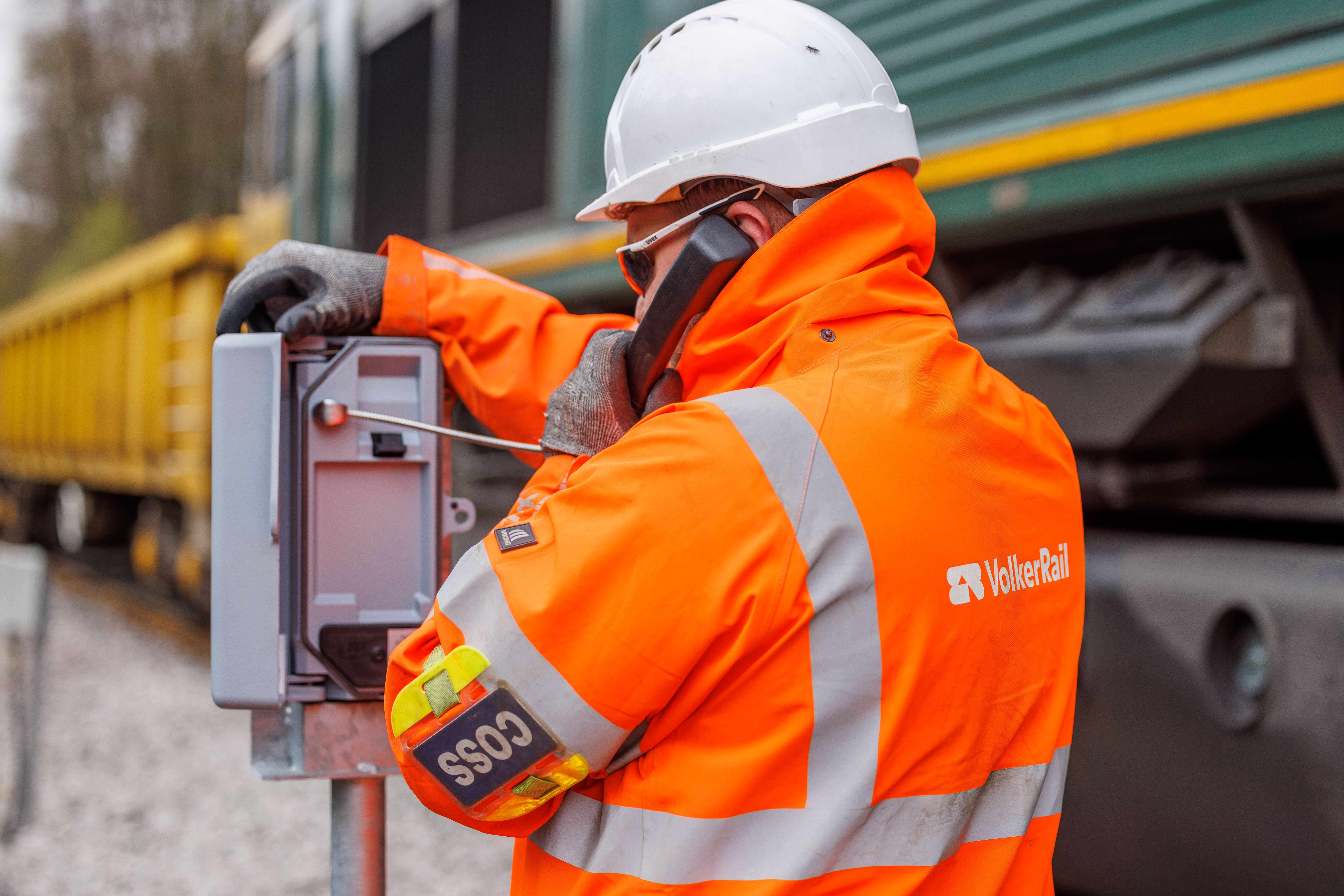 man in orange PPE testing telecoms equipment on track