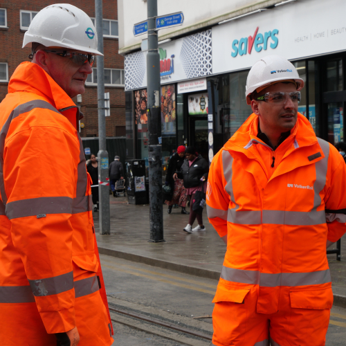 Two men in orange PPE on a tram site