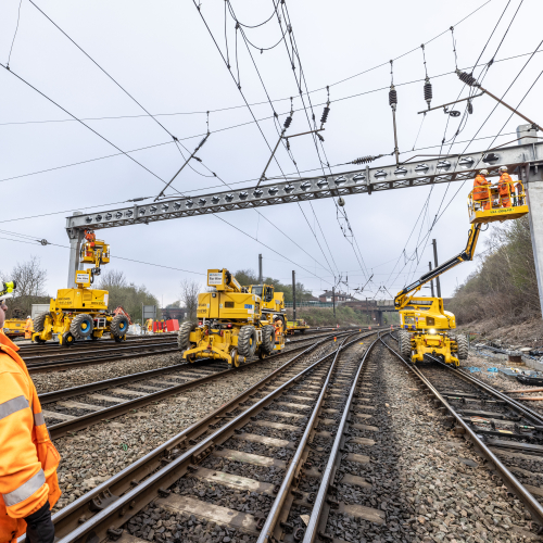 Rail operative looking up at an overhead line gantry being installed by VolkerRail using MEWPS and road rail vehicles on the Transpennine route upgrade project