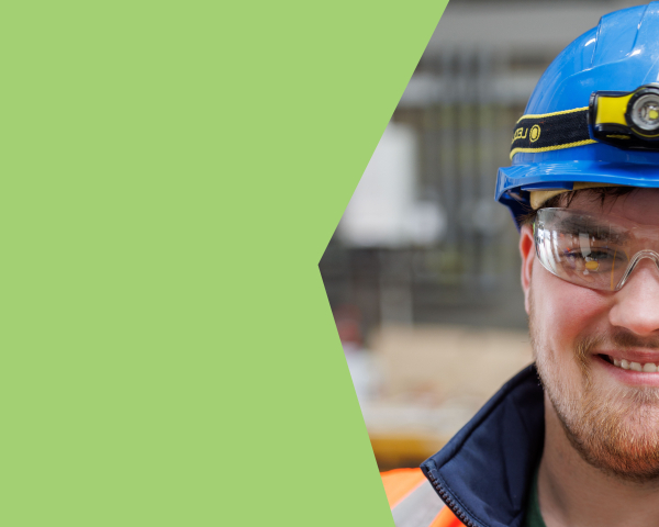 A young man in orange PPE and blue hard hat smiling