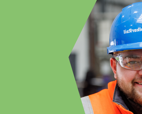 A young man in orange PPE and blue hard hat smiling